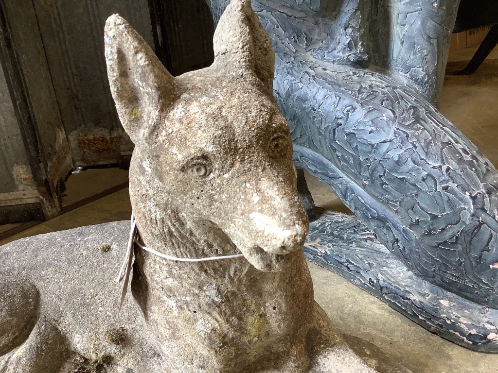 A reconstituted stone garden ornament of a recumbent German Shepherd dog, length 50cm
